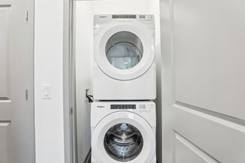 A white washing machine and dryer in a laundry room. at The Junction at Rockledge Apartments, Rockledge